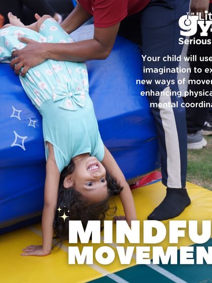 With an instructor's support, a young girl practices a supported handstand. This is a safe way to introduce inversions, helping children build confidence while learning to trust their bodies and their teachers.