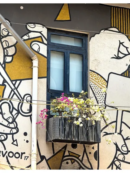 A window box overflowing with bougainvillea adds a splash of life to a building covered in graphic art.