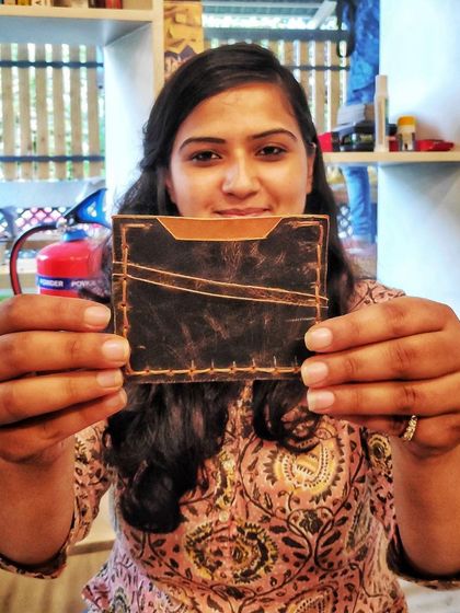 A happy participant showing off the custom leather wallet she made in our workshop. There's nothing like the pride of holding a beautiful, functional item you've created with your own hands.