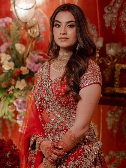 A close-up portrait of the bride, showcasing her stunning red lehenga and intricate jewelry, which perfectly complemented the opulent decor.