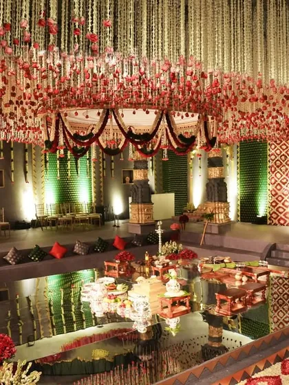 The reflection of the floral canopy and intricate decor in the mirrored water feature, adding another layer of depth and beauty to the wedding mandap.