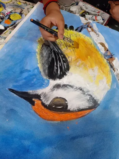A student painting a colorful bird, focusing on blending and layering acrylics to create a soft, feathered effect.