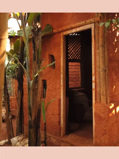 The entrance to a cob and wattle-and-daub structure, showing the raw, organic texture of the mud walls.