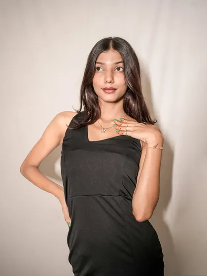 A close-up portrait focusing on the model's mysterious expression and the simple elegance of her black dress and necklace.