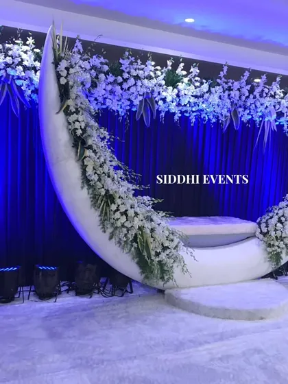 For a truly magical photo opportunity, we created this custom moon-shaped seat, adorned with delicate white florals against a deep blue backdrop, perfect for celebrating an anniversary or reception.