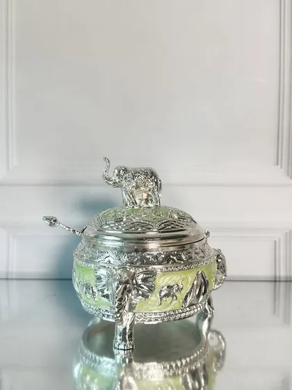 The elephant-topped dry fruit box in a refreshing lime green enamel. The detailed silver work and elephant motif make it a unique and auspicious piece for any festive occasion.