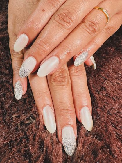 A beautiful contrast of pearly white and full-coverage silver glitter on almond-shaped nails. It's a simple way to add a lot of sparkle.