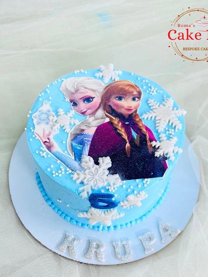 A simple and sweet Frozen-themed cake with an edible image of Elsa and Anna, surrounded by fondant snowflakes.