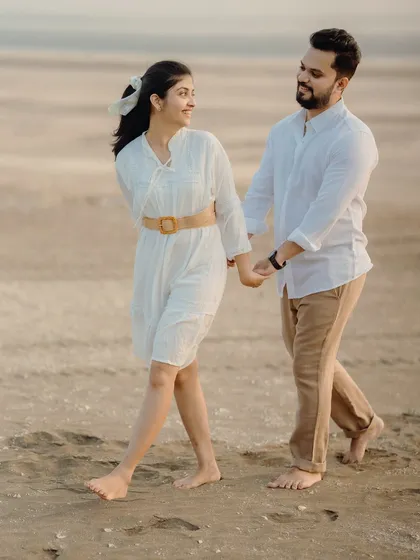 A candid walking shot on the sand. The natural movement and interaction between Milan and Pranali make this pre-wedding photo feel genuine and full of life.