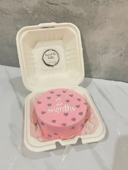 A cute pink bento cake to celebrate a baby's two-month milestone. It's decorated with little grey hearts and the message "2 months."