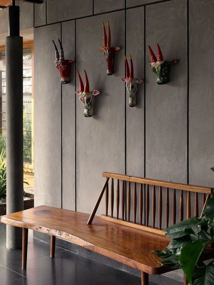 An interior detail from the 'House in the Tropics', where a live-edge wooden bench is paired with whimsical ceramic animal heads, adding a touch of personality.