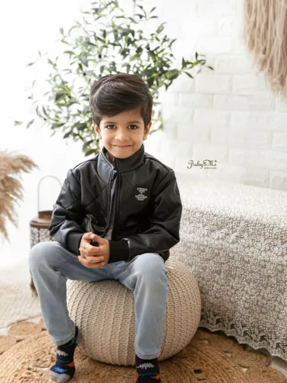 A handsome young boy posing for his portrait. The leather jacket adds a cool touch to his look during this fun family photoshoot.