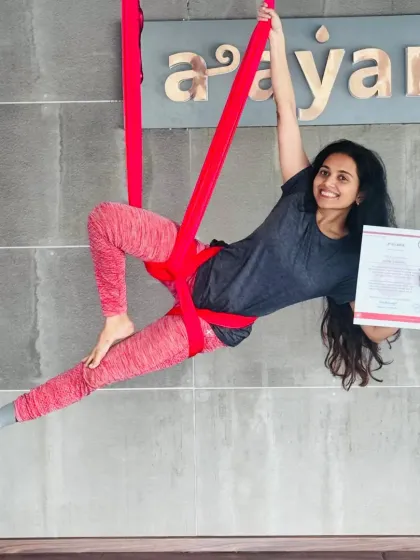 Striking a graceful pose with her certificate, this student embodies the blend of art and athleticism that is aerial yoga.