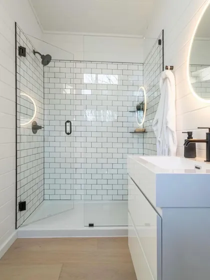 A close-up of a modern bathroom in one of our modular homes. The design features a clean, white-tiled shower, minimalist fixtures, and excellent lighting, proving that luxury is in the details.