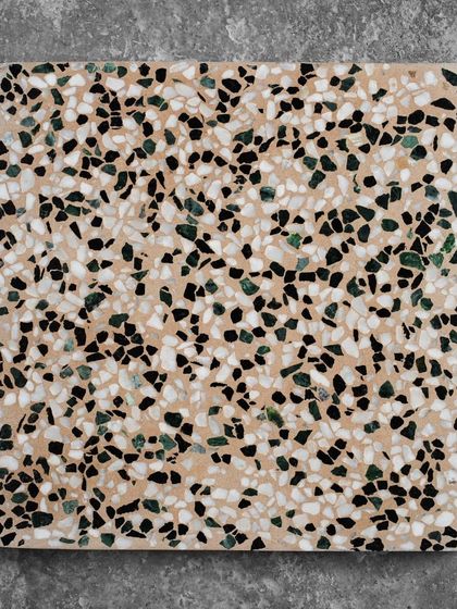 A single tile of the beige terrazzo with green and black chips, offering a more neutral but still visually interesting option.