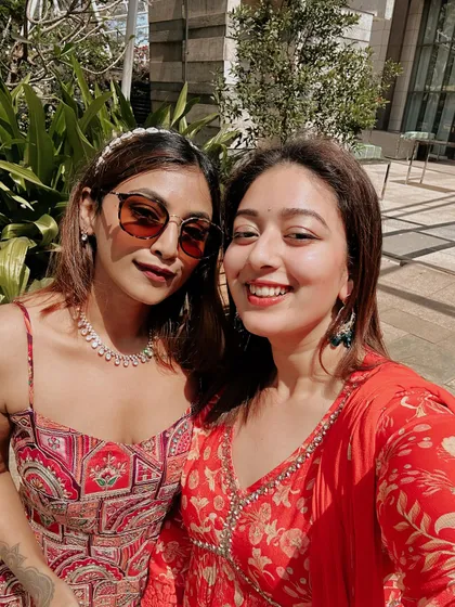 A sunny selfie with a friend during a wedding celebration. I'm wearing a red and orange patterned sundress, a great option for a daytime wedding event.
