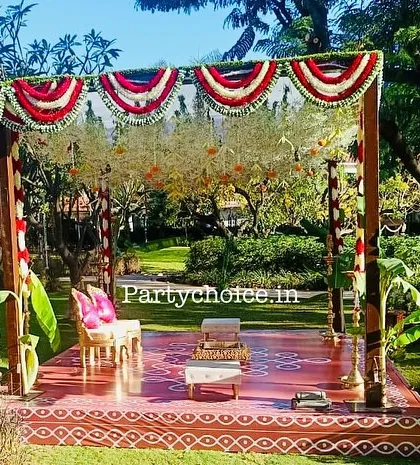 We created this authentic, traditional outdoor mandap using a wooden frame and natural elements. The design includes red and white floral garlands, banana leaf accents, and a custom-printed floor with kolam patterns for a culturally rich ceremony.
