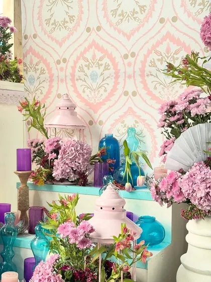 A pretty corner from the Kashmiri event, featuring pink lanterns, blue glass vases, and purple candles set against a traditional patterned wallpaper. These details added pops of color and local flavor.