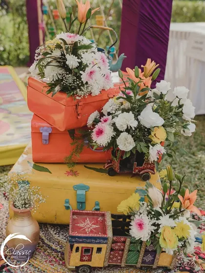 I love adding quirky and personal elements. For this travel-themed couple, I used colorful miniature trucks and suitcases as unique planters for the floral arrangements.