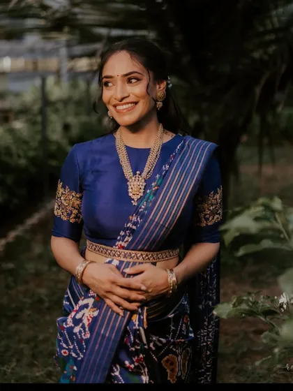 This client is wearing a royal blue saree with a matching blouse that features delicate gold embroidery on the sleeves, a subtle yet elegant touch.