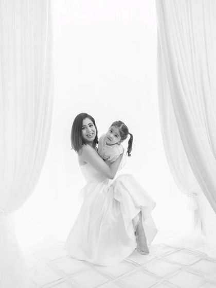 A mother holds her daughter in a joyful embrace in this high-key black and white photograph. It’s a legacy of love in every frame, a timeless image of happiness and connection.