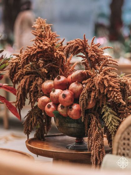 A bowl of pomegranates and dried botanicals, a symbolic detail from the 'Orchard of Life' naming ceremony representing abundance and prosperity.