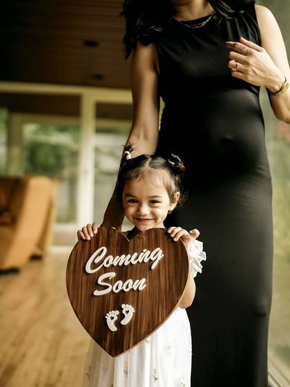 The pure joy of a big sister to be. Her bright smile while holding the "Coming Soon" sign is infectious and makes for a heartwarming family pregnancy announcement.