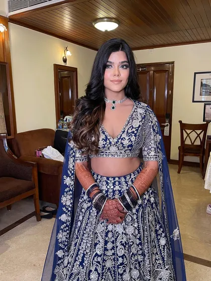 Soft waves with a center part for a sangeet look, complementing a heavily embroidered lehenga.