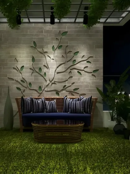 Designed for cozy evenings, this balcony features a comfortable sofa set against a wall with a unique, tree-branch metal art installation. The entire floor is covered with soft artificial grass, and the space is lit to create a dramatic, intimate ambiance against the city skyline.