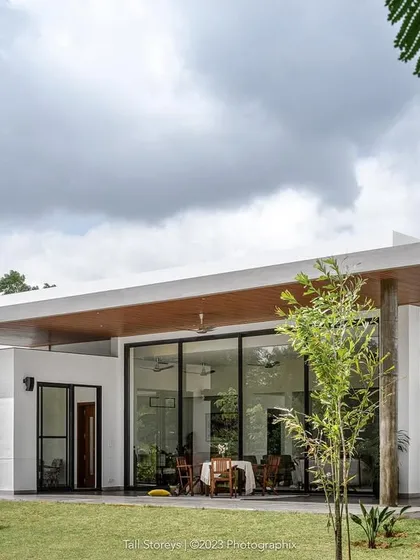 A view of our project, "Nisarg," a contemporary farmhouse near Bengaluru. The design blurs the line between indoors and outdoors, with expansive glass walls that open the living spaces to the garden and the forest beyond.