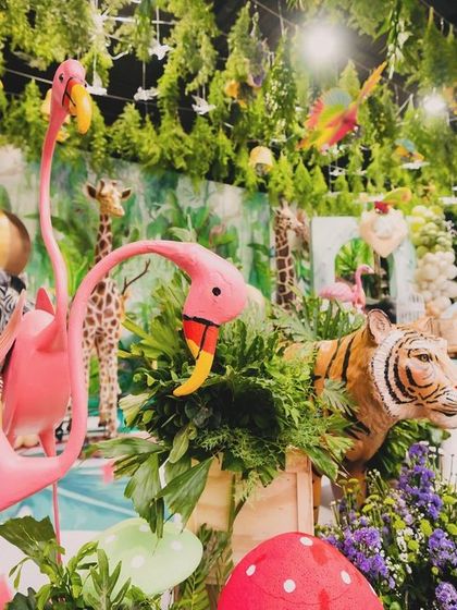 Another look at the dense and detailed decor for Eshaan's safari, with pink flamingos, a tiger, and a zebra nestled among lush plants and flowers.