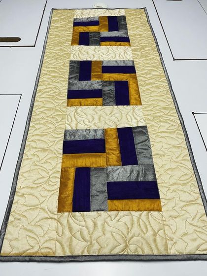 An angled view of the silk table runner, highlighting the sheen of the fabric and the elegant quilting.