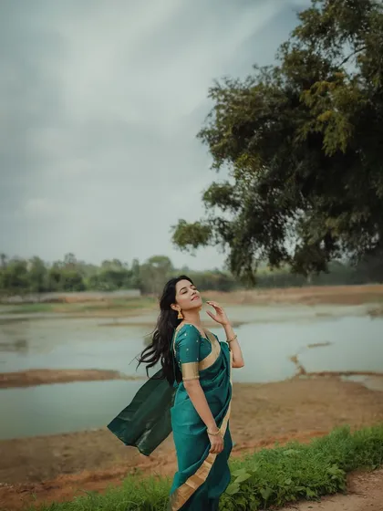 Mirnalini Ravi enjoying the breeze during her outdoor shoot. The flowing saree and hair create a sense of movement and freedom.