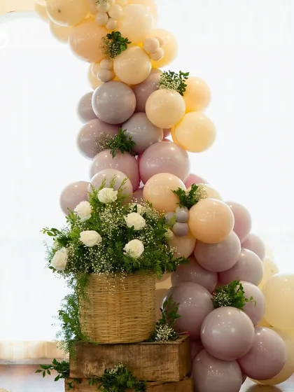 A detailed shot of the balloon arch and fresh floral arrangement in a wicker basket. This combination of elements added a rustic yet elegant touch to the baby shower decor.
