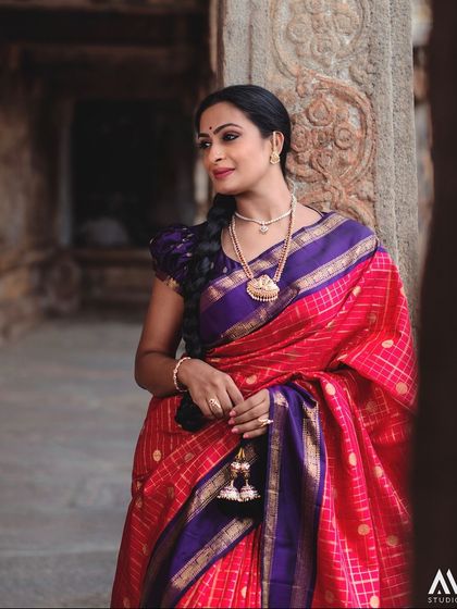 Leaning against an ancient pillar, the model's pose is one of quiet contemplation. The rich colors of her saree stand out against the stone.