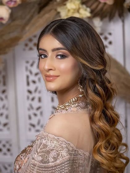 A soft, glowing sangeet look. The makeup features a beautiful shimmer on the eyes and a glossy nude lip, paired with soft waves for a romantic and dazzling evening style.