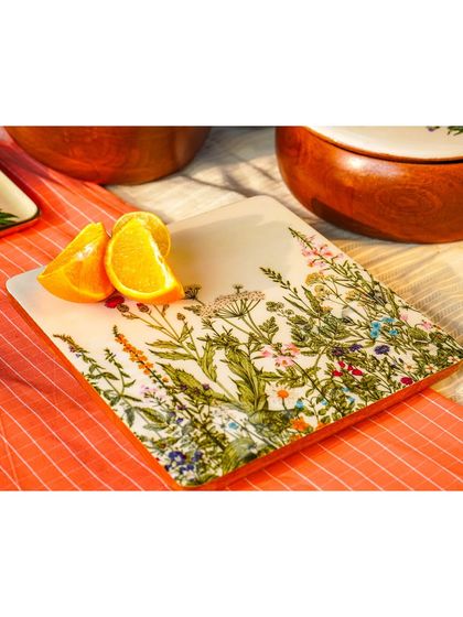 A close-up of a square plate with a wildflower design, shot outdoors in natural light. This highlights the delicate, hand-painted details.