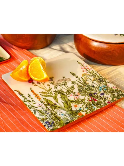 A close-up of a square plate with a wildflower design, shot outdoors in natural light. This highlights the delicate, hand-painted details.