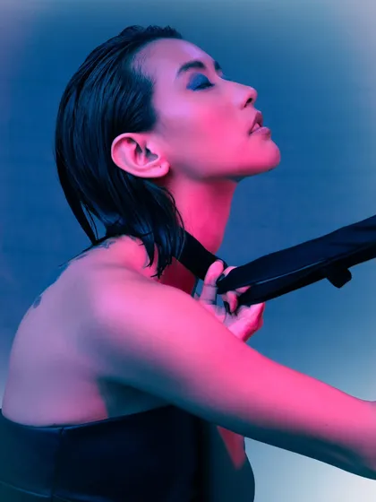 This portrait uses a mix of pink and blue gel lighting to create a vibrant, cyberpunk feel. The focus is on the mood and color, with the model's pose adding a sense of drama.