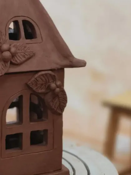 A side view of the clay house lantern, showing the carefully carved windows and sculpted leaf decorations. Every angle of the piece is considered in the design process.