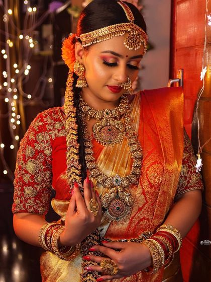 A beautiful bride adorned in our heavy temple jewellery, ready for her muhurtham. The fairy lights in the background add a magical touch to this stunning photo.