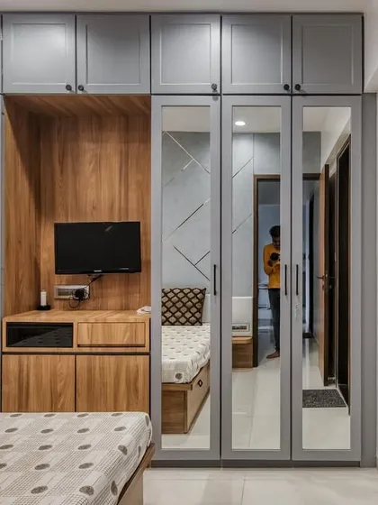 This bedroom features a floor-to-ceiling wardrobe with mirrored doors, which helps make the space feel larger. An integrated TV unit and study nook maximize functionality.