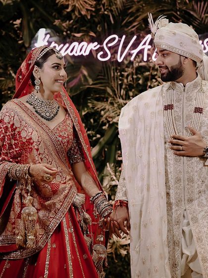 A beautiful candid moment between the bride and groom on their wedding day in Delhi. The neon sign in the background adds a modern touch to this heartfelt, traditional moment.