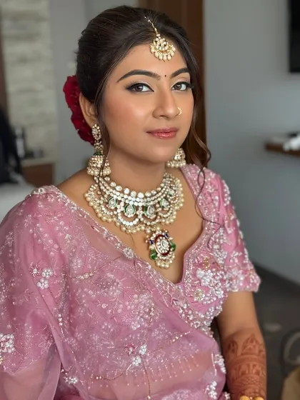 The bride looks radiant and happy. Her full makeup look, with glowing skin and soft pink tones, complements her pastel lehenga perfectly.
