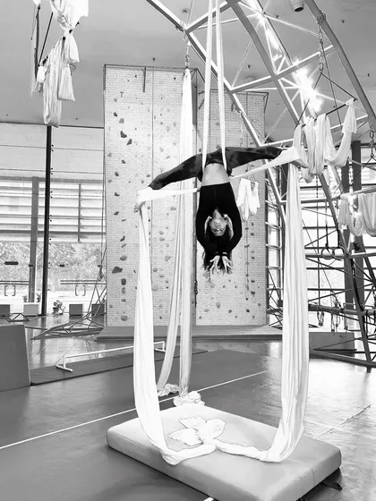 A striking black and white photo of an aerialist in an inverted straddle. This highlights the beautiful lines and shapes you can create with your body.