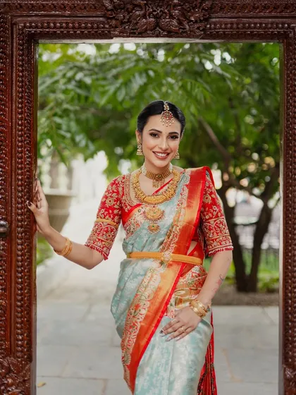 A smiling portrait of the bride, framed by the ornate doorway. Her makeup is bright and enhances her joyful expression.