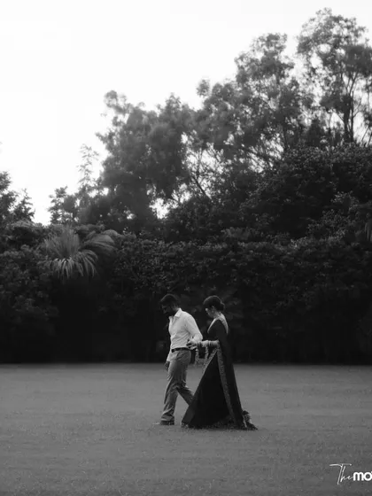 A wide, minimalist black and white shot of a couple walking across a vast lawn in Jammu. The simplicity of the composition emphasizes their connection and journey together.