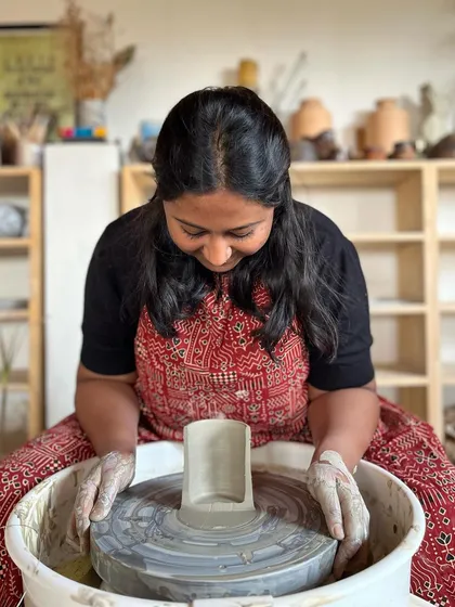 A professional course student proudly displays a cross section of her thrown cylinder, showing the even wall thickness she achieved through dedicated practice.