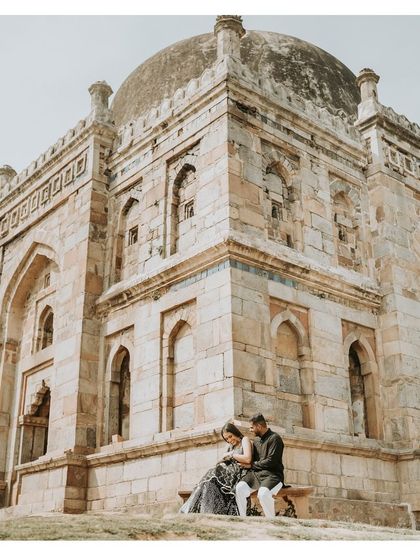 A quiet, romantic moment for a couple seated before a historic stone monument in Delhi, blending their modern love story with the echoes of the past.