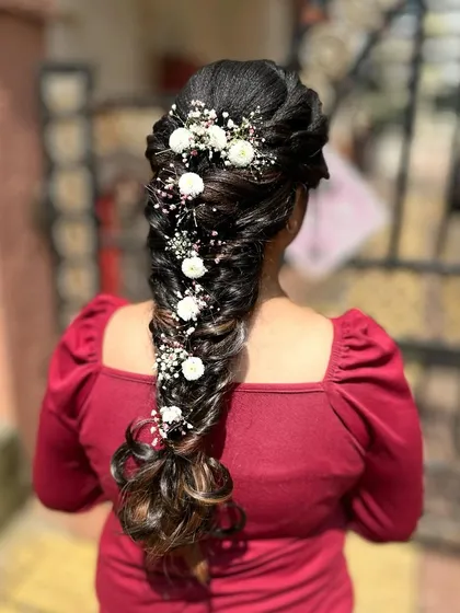 This is a messy mermaid braid, a popular choice for weddings and special events. I created this look by weaving together different sections and incorporating delicate baby's breath and white flowers for a romantic touch. It's an intricate style that looks both elegant and effortless.
